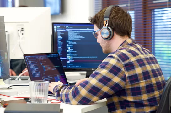 Person sitting at a table, reviewing code on a laptop screen, illustrating the development process for a Minimum Viable Product (MVP).